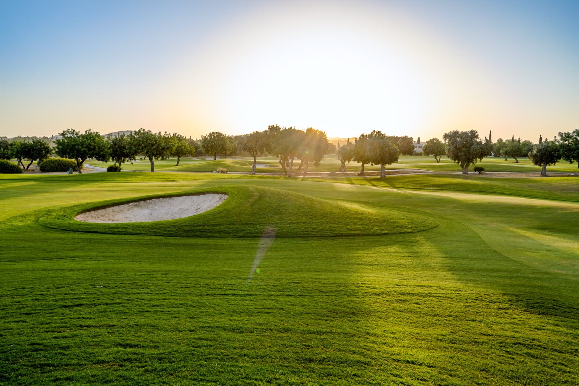 Golden-hour ground-level view of a bunker and fairway at Aphrodite Hills, captured by Backlight Media