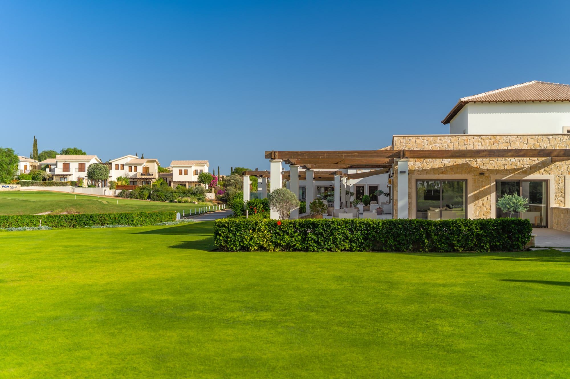 The clubhouse and villas beside the manicured lawns at Aphrodite Hills, documented by Backlight Media