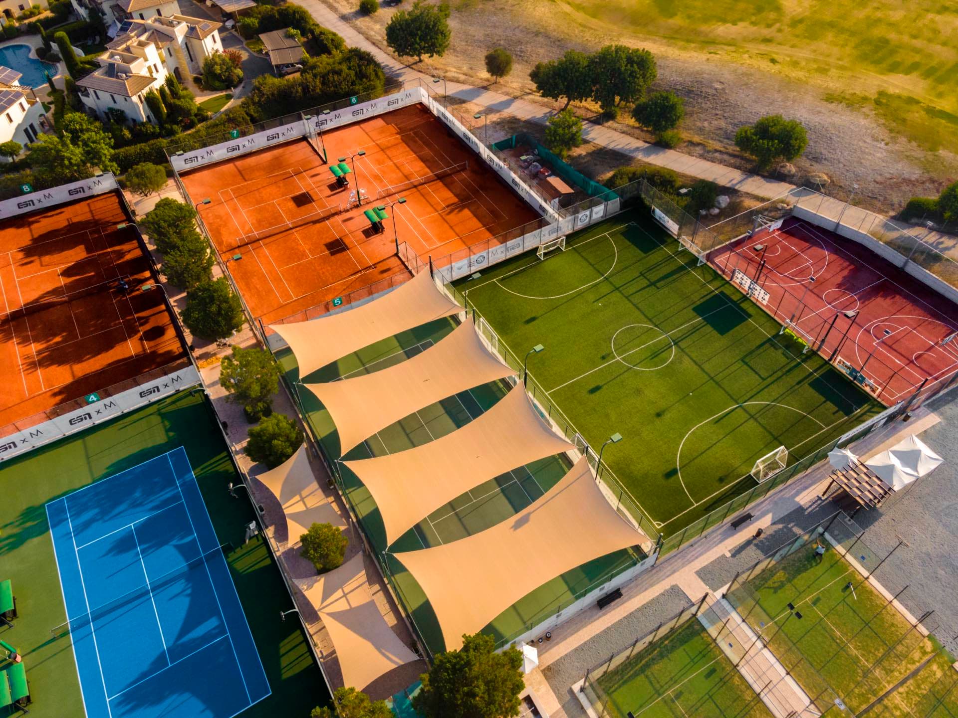 Aerial view of the tennis academy and sports facilities at Aphrodite Hills, including clay and hard courts, shot by Backlight Media