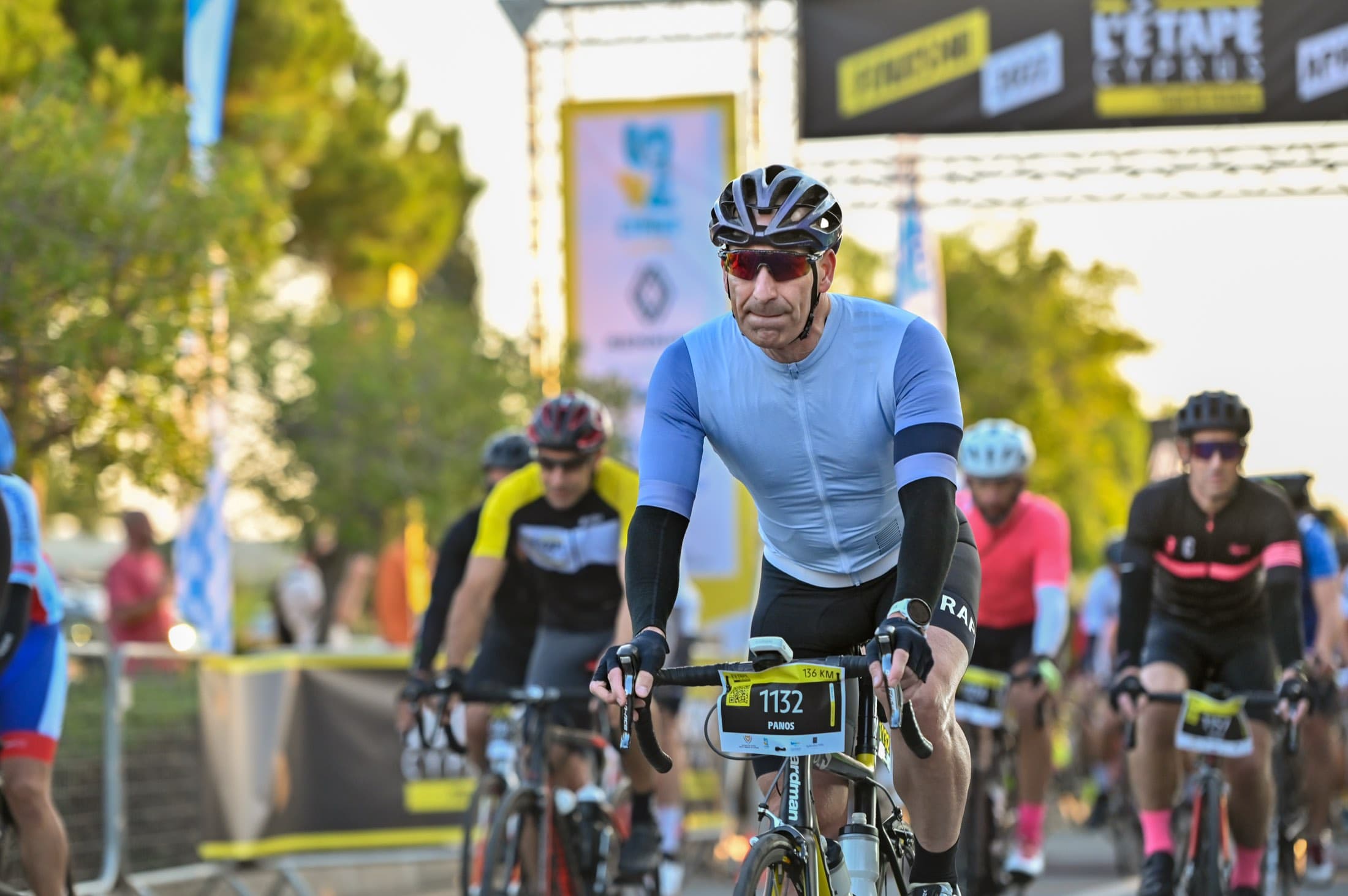A rider crosses the L'Étape Cyprus start gantry at first light, captured on the day by Backlight Media, Tour de France mass-participation race in Cyprus