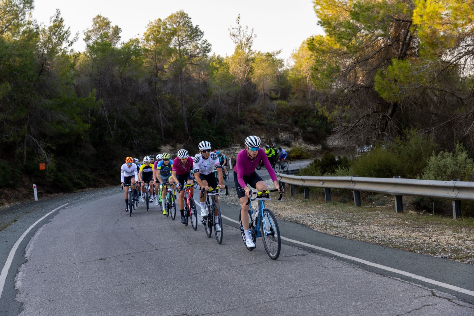 Riders climb a forested mountain road on the L'Étape Cyprus route, Tour de France, shot on the day by Backlight Media in Cyprus